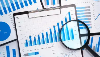 magnifying glass on top of a clipboard showing charts