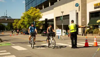 People biking on the street and traffic control officers directing traffic.