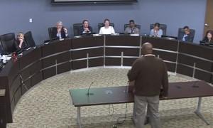 Photo of a person speaking to a panel at a public meeting