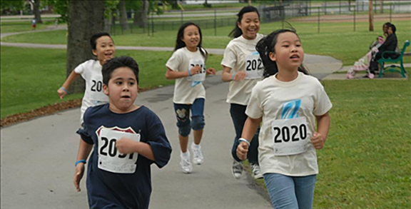 Photo of children running a race with competitor numbers.