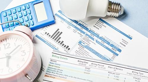 Photo of several utility bills and a calculator and clock