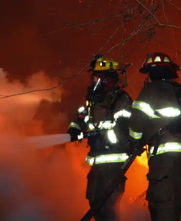 firefighters putting out fire with hose