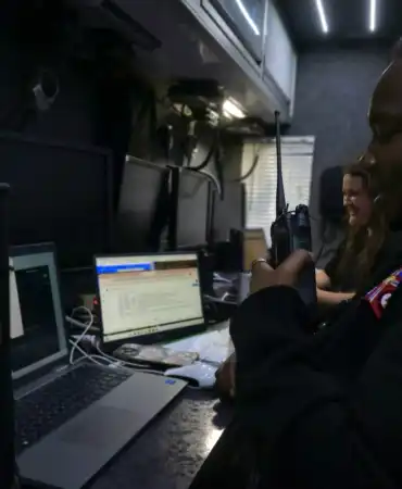 woman sitting in front of a computer and holding a two way radio